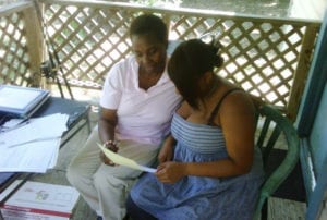 Younger woman looking at a paper sitting next to an older woman on a porch